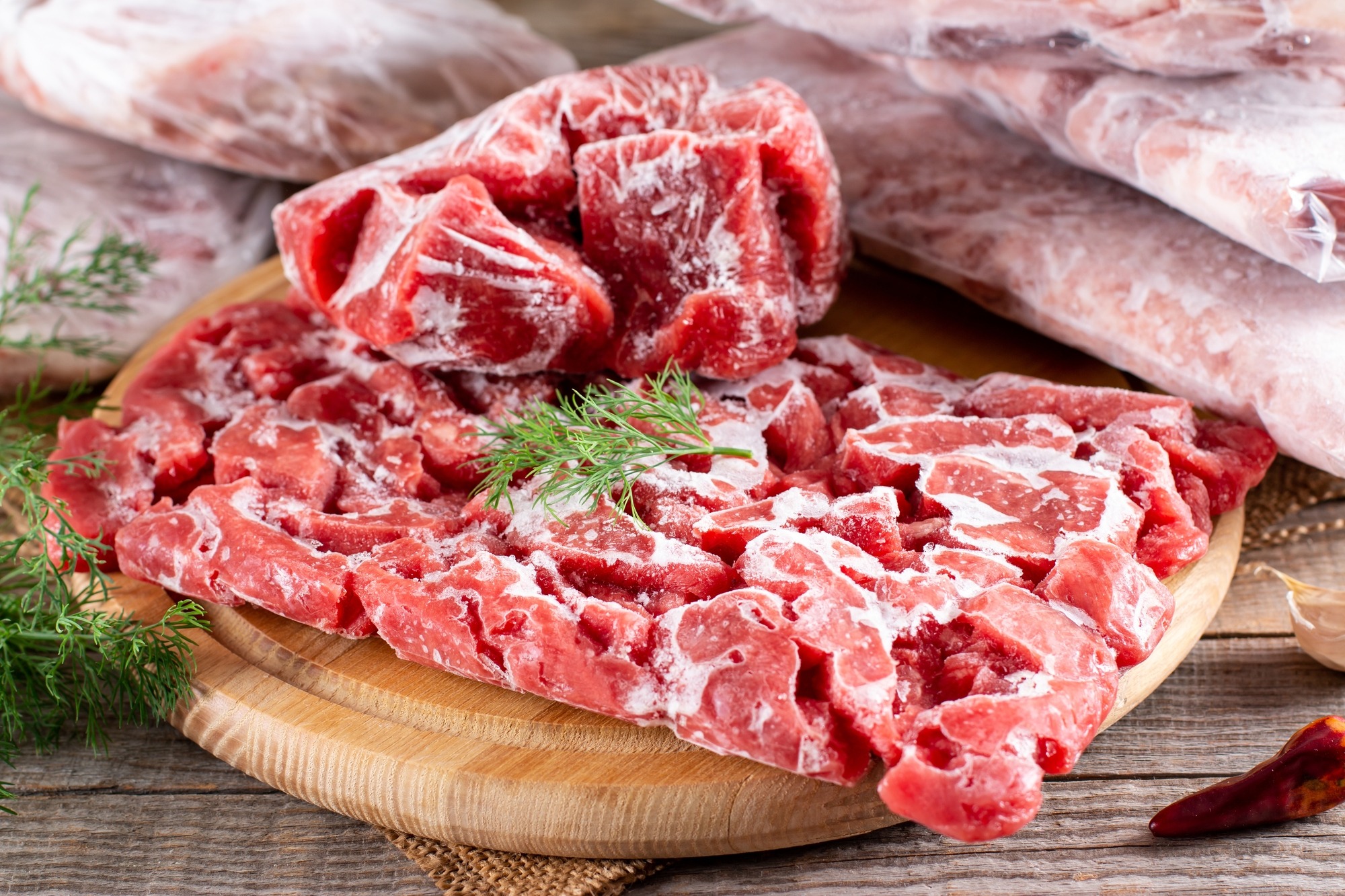 Frozen Raw Meat in a Plastic Bag on a Wooden Table.